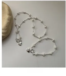 Macro detail of S925 silver heart pendants and pearls on necklace and bracelet set