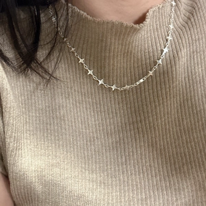 Elegant S925 sterling silver four-pointed star necklace on model with knit background