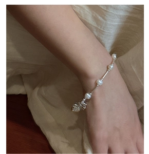 Macro shot of S925 silver heart charm and pearl bracelet worn on a female wrist