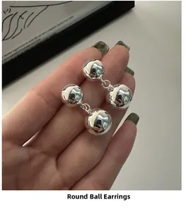 Close-up of polished S925 sterling silver double ball drop earrings held in hand