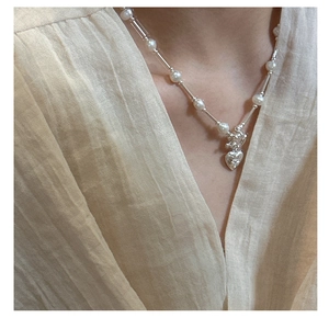 Detail of S925 silver necklace with white pearls and a 3D bear heart pendant on model