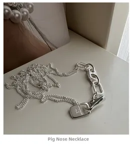 Detail of S925 silver necklace with asymmetric chain links and engraved rectangular tag