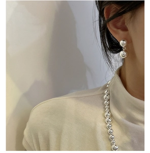 Close-up of minimalist silver double sphere earrings and matching beaded chain on a model