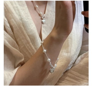 Detailed view of silver heart pendant with star engraving on pearl necklace and bracelet
