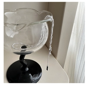 Detail of S925 sterling silver layered necklace draped on a glass with beaded chain