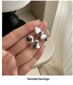 Macro shot of silver twisted metal earrings showing polished liquid metal texture