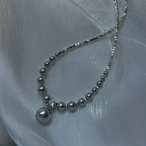 Detail of grey pearl gradient necklace with zircon pendant on silver silk background