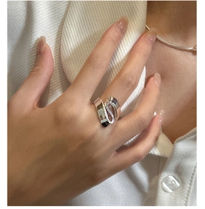 Macro view of wide S-shaped layered sterling silver ring worn by a model