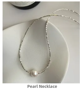 Detailed top view of a round Edison pearl on a silver block chain over a white ceramic plate