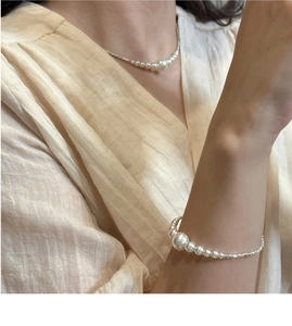 Detail of gradient pearl necklace and bracelet set on model with linen clothing