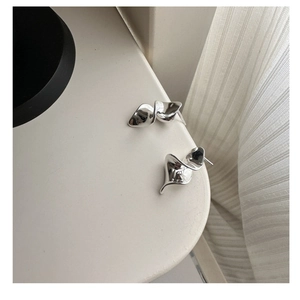 Macro detail of S925 sterling silver ruffled earrings with minimalist spiral liquid texture