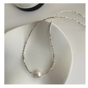 Detail of S925 sterling silver necklace with shiny small beads and a large white Edison pearl