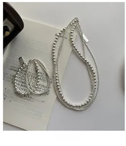Detail of S925 sterling silver beaded necklace and bracelet set layered on a book
