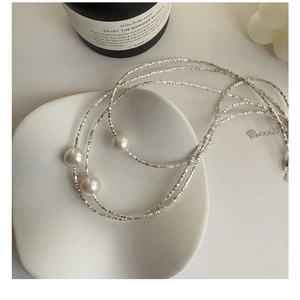 Detailed macro view of S925 sterling silver pearl necklace on an elegant ceramic plate
