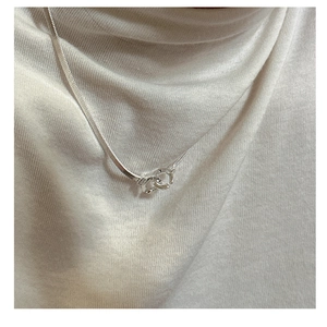 Detail of S925 silver double ring necklace with engraved joy charm on a white sweater