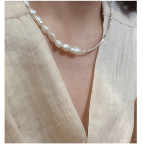 Detailed view of S925 silver necklace with irregular baroque pearl on a female model