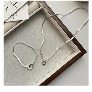 Detailed close-up of S925 silver snake bone necklace and bracelet set in a jewelry tray