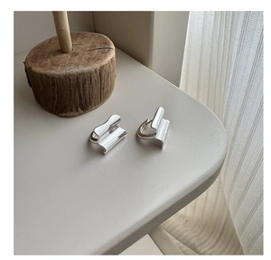 Macro detail of silver S925 geometric wave earrings with polished pleated texture