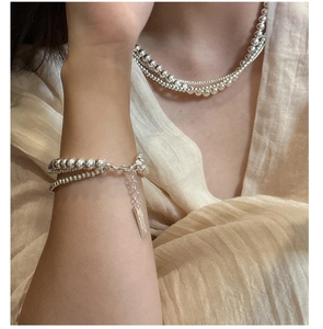 Detail of layered S925 sterling silver beaded necklace and bracelet set on model