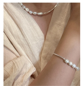 Detail of baroque pearl and silver bead necklace set on a model in vintage style