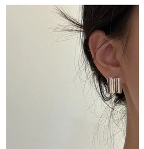 Close-up of woman wearing a silver S925 sterling silver wavy square hoop earring