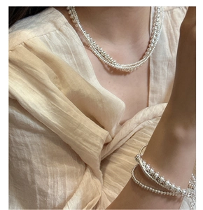 Detail of layered S925 sterling silver beaded necklace and bracelet set on model