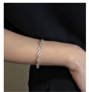 Close-up of S925 sterling silver infinity knot bracelet worn on woman's wrist