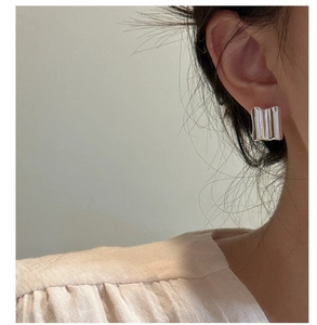 Detail of minimalist S925 sterling silver rectangular hoop earring with wavy texture