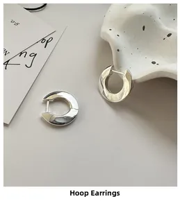 Macro detail of minimalist S925 sterling silver hoop earrings with irregular glossy finish