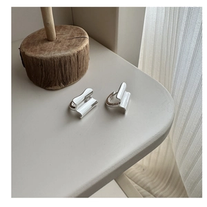 Macro detail of geometric silver earrings with unique wavy wrinkled texture and polish
