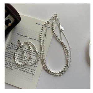 Detailed view of S925 sterling silver beaded necklace and layered bracelet on a book
