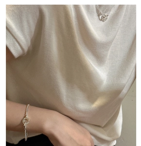 Detail of silver S925 double-ring buckle bracelet and necklace worn by a model