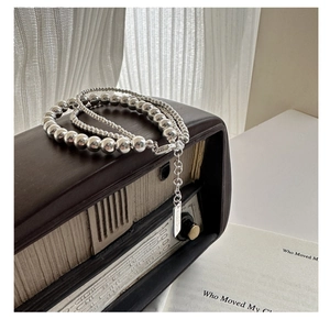 Close-up of triple-layer S925 sterling silver bead necklace with a metallic logo tag