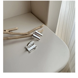 Detailed view of S925 sterling silver stamp on minimalist wave pattern square earrings