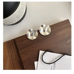 Detail von S925 Silber gefalteten runden Ohrringen auf dunklem Walnussholz-Display