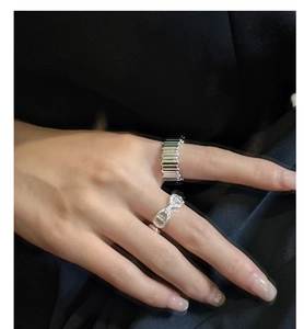 Detail of stacked S925 sterling silver rings with striped design and geometric link