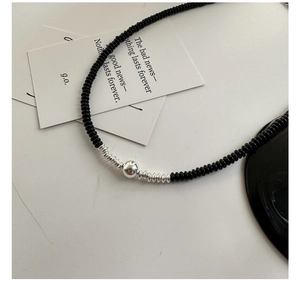 Detailed view of 925 sterling silver beads and black onyx stones on a minimalist necklace