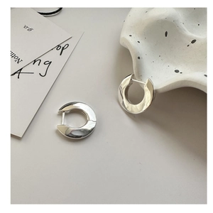Detailed view of glossy S925 sterling silver hoop earrings on a ceramic tray