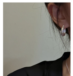 Close-up of S925 sterling silver hoop earrings with intricate floral relief on model