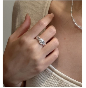 Close-up of s925 silver heart ring with braided chain band on a model finger