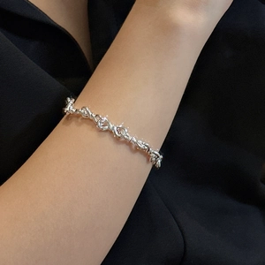 Minimalist S925 sterling silver figure-8 knot chain bracelet shown on woman wrist