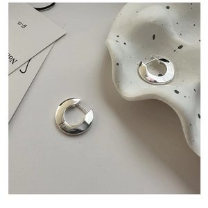 Macro detail of high-polish S925 sterling silver hoop earrings with secure clasp