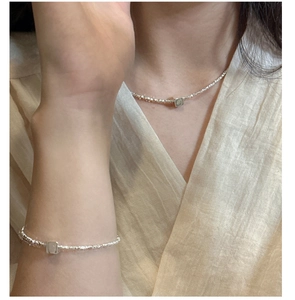 Détail du collier et bracelet en argent S925 avec pendentif carré porté par un mannequin