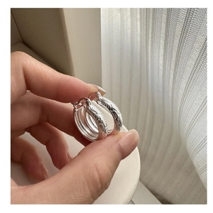 Detailed macro view of S925 sterling silver hoop earrings with vintage embossed floral patterns