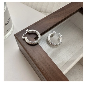 Detailed macro view of S925 sterling silver hoop earrings with vintage floral engravings