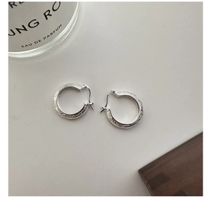 Macro detail of S925 sterling silver hoop earrings with intricate retro floral engraving
