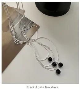 Detailed view of silver snake chains featuring minimalist black agate bead pendants