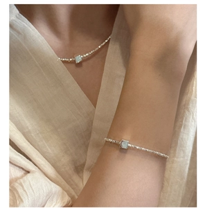 Détail de l'ensemble collier et bracelet en argent avec pendentif carré porté sur modèle