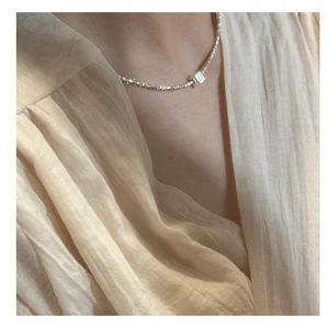 Gros plan sur collier en argent massif S925 avec perles concassées et cube géométrique