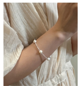 Détail du collier en argent S925 et perles d'eau douce sur le poignet pour un look doux